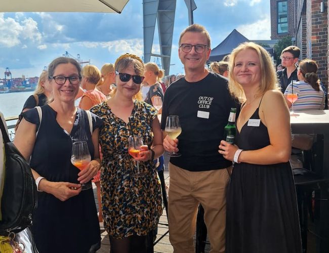 Teilnehmende beim Sommerfest 2026 in Hamburg auf der Terrasse mit Blick auf die Elbe. 